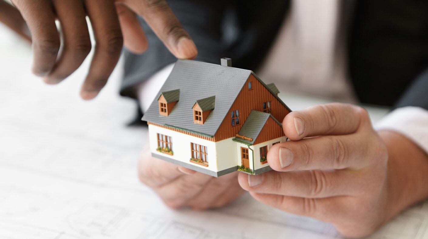 500sqm or 300sqm: Which Plot Size Is Right for You? close up shot of caucasian contractor holding real estate project while his african colleague pointing finger at scale model building, explaining design during presentation meeting in office