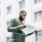 man reading newspaper near glass fence